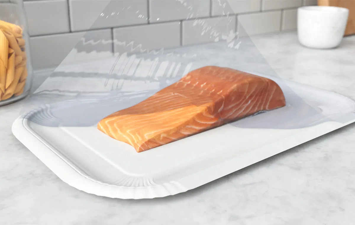 A piece of salmon on a coated paperboard tray with a plastic film cover.