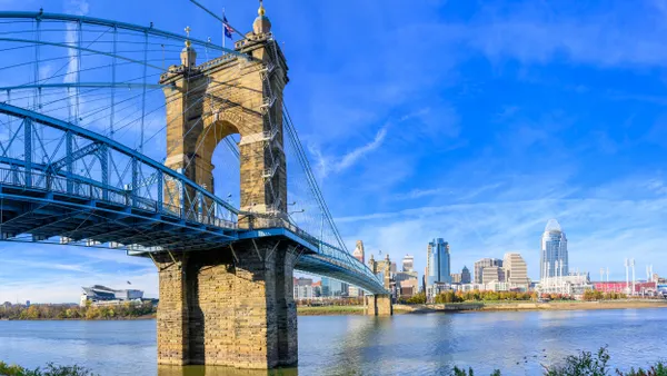 A bridge over a large river with city skyline beyond.
