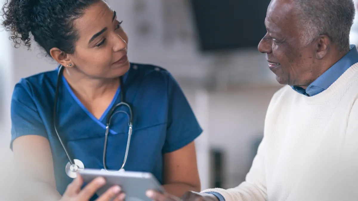 Doctor conversing with tablet to elderly patient.