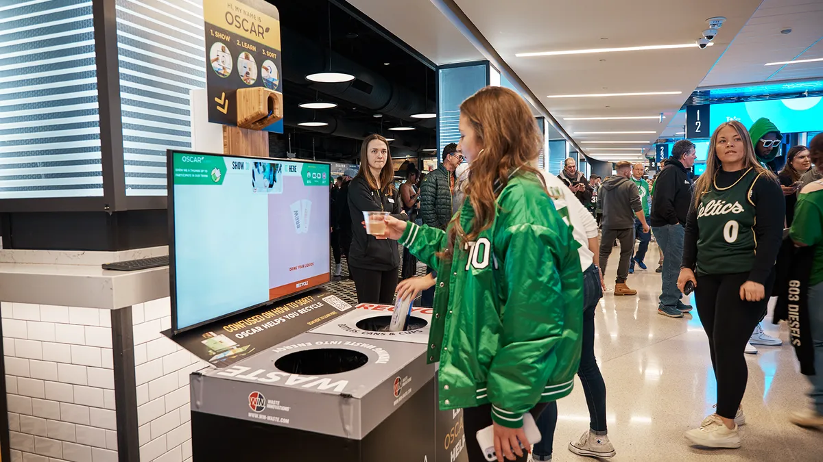 Fans interact with the Oscar Sort screen. The screen tells them which bin to put trash and recycling items.