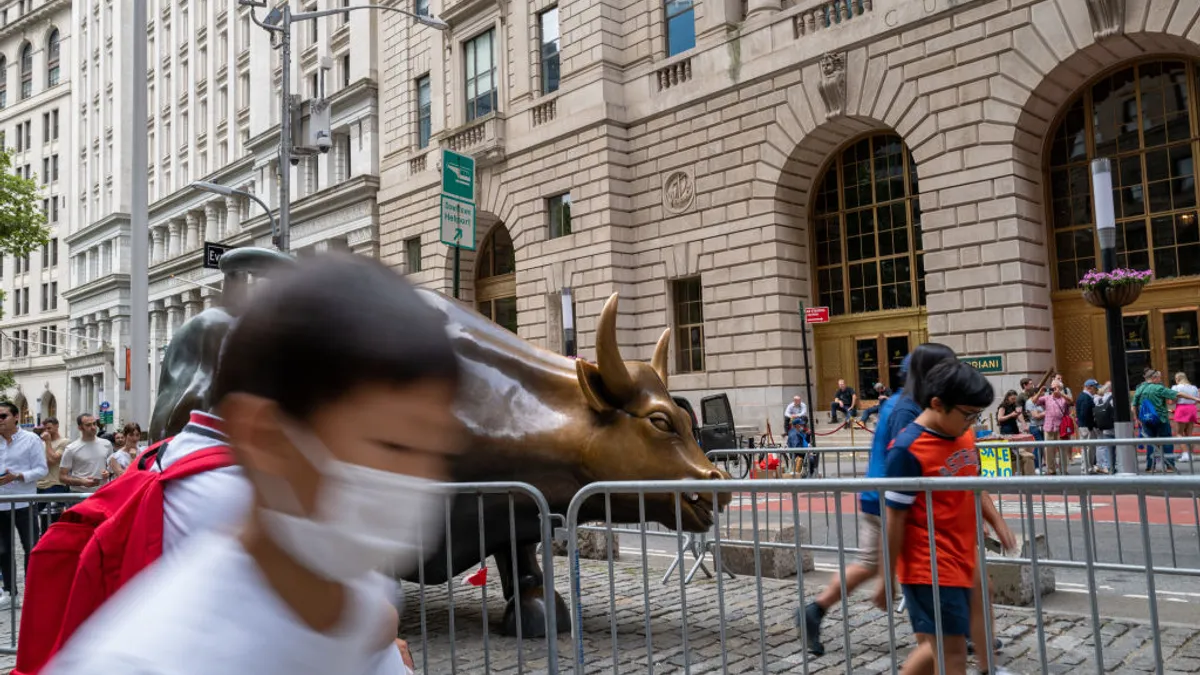 People pose with the Wall Street Bull in the financial district in Manhattan on June 14, 2022 in New York City.