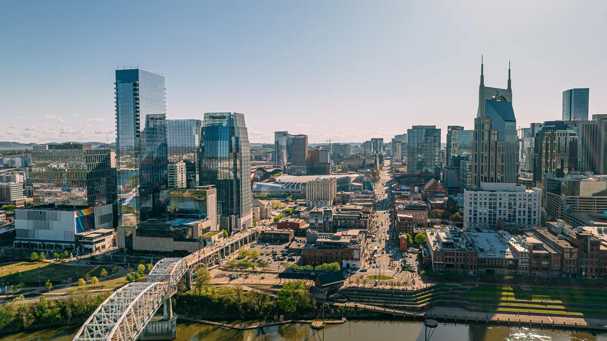 A shot of Nashville from above a river, among the city's buildings.