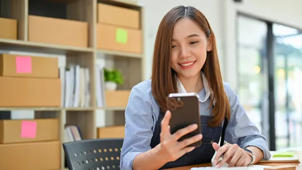 Beautiful Asian female e-commerce business startup using her mobile phone