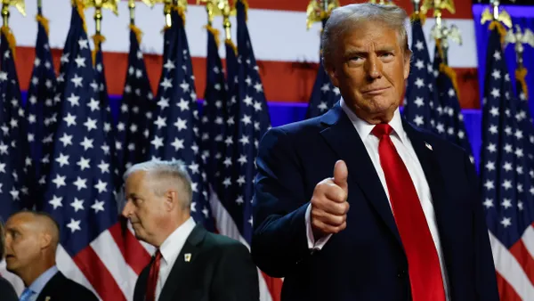 President-elect Donald Trump giving the thumbs-up against a background of U.S. flags.