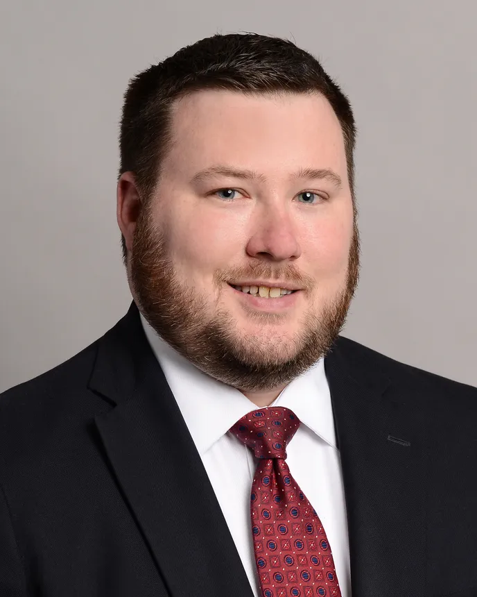 Headshot of a brown haired man in a suit.