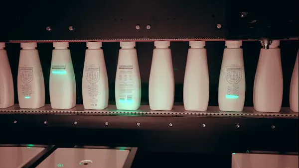 Numerous white bottles with light gray markings sit in a line.
