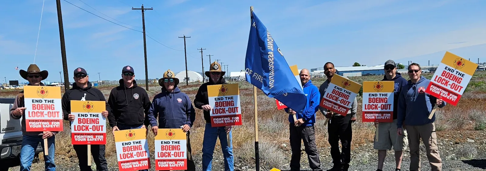 Nine people wearing jackets and holding lockout picket signs.