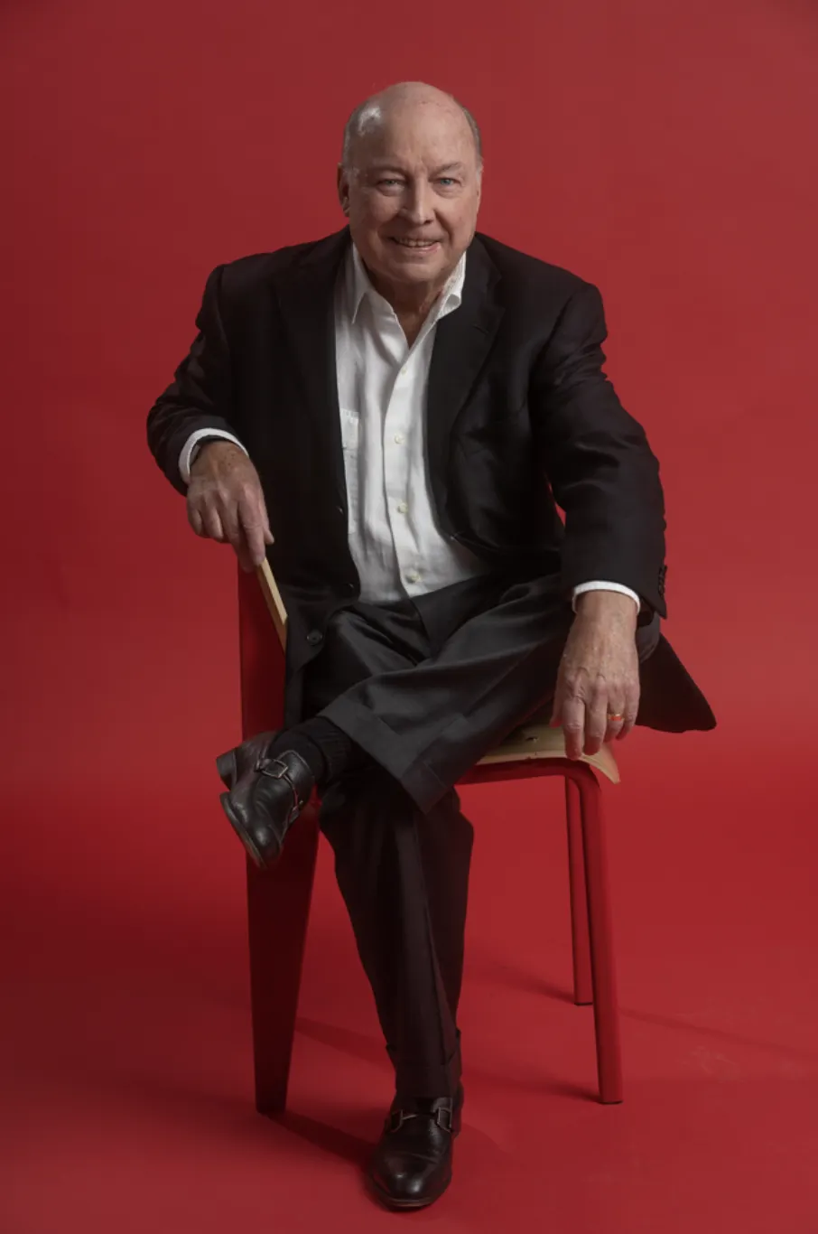 A full-body photo of a person against a red background.