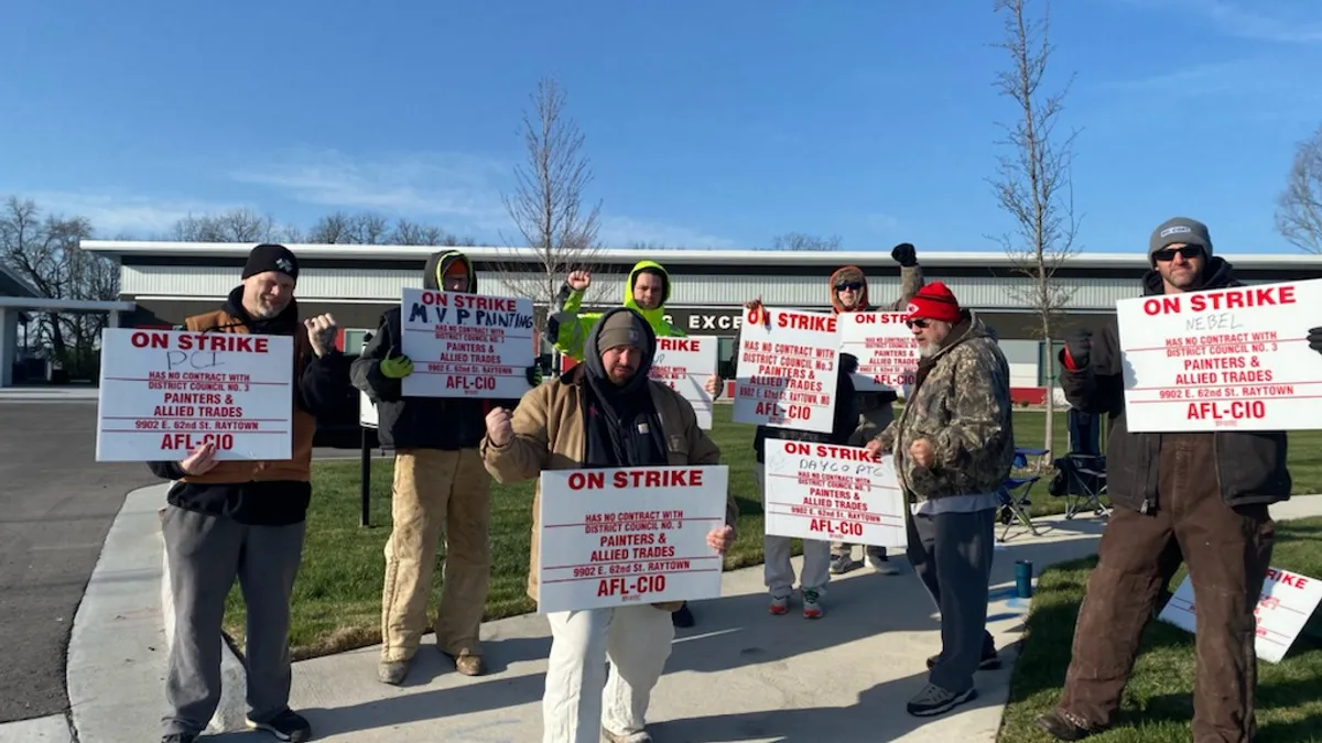 Members of the International Union of Painters and Allied Trades hold signs in protest, striking for higher wages.