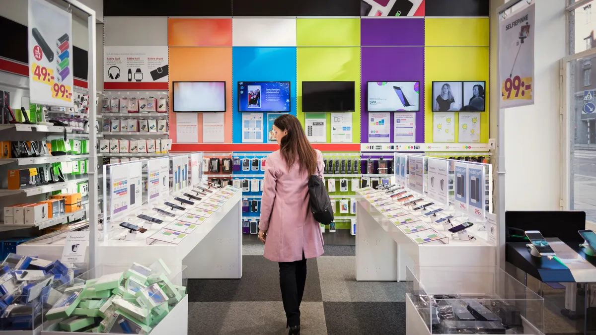 Rear view of female customer viewing smart phones in store