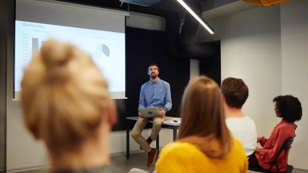 A group of people face a person giving a presentation.