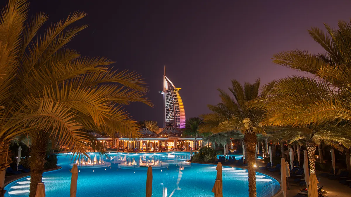 The sail-shaped Burj al Arab hotel in Dubai as seen at night from a pool.