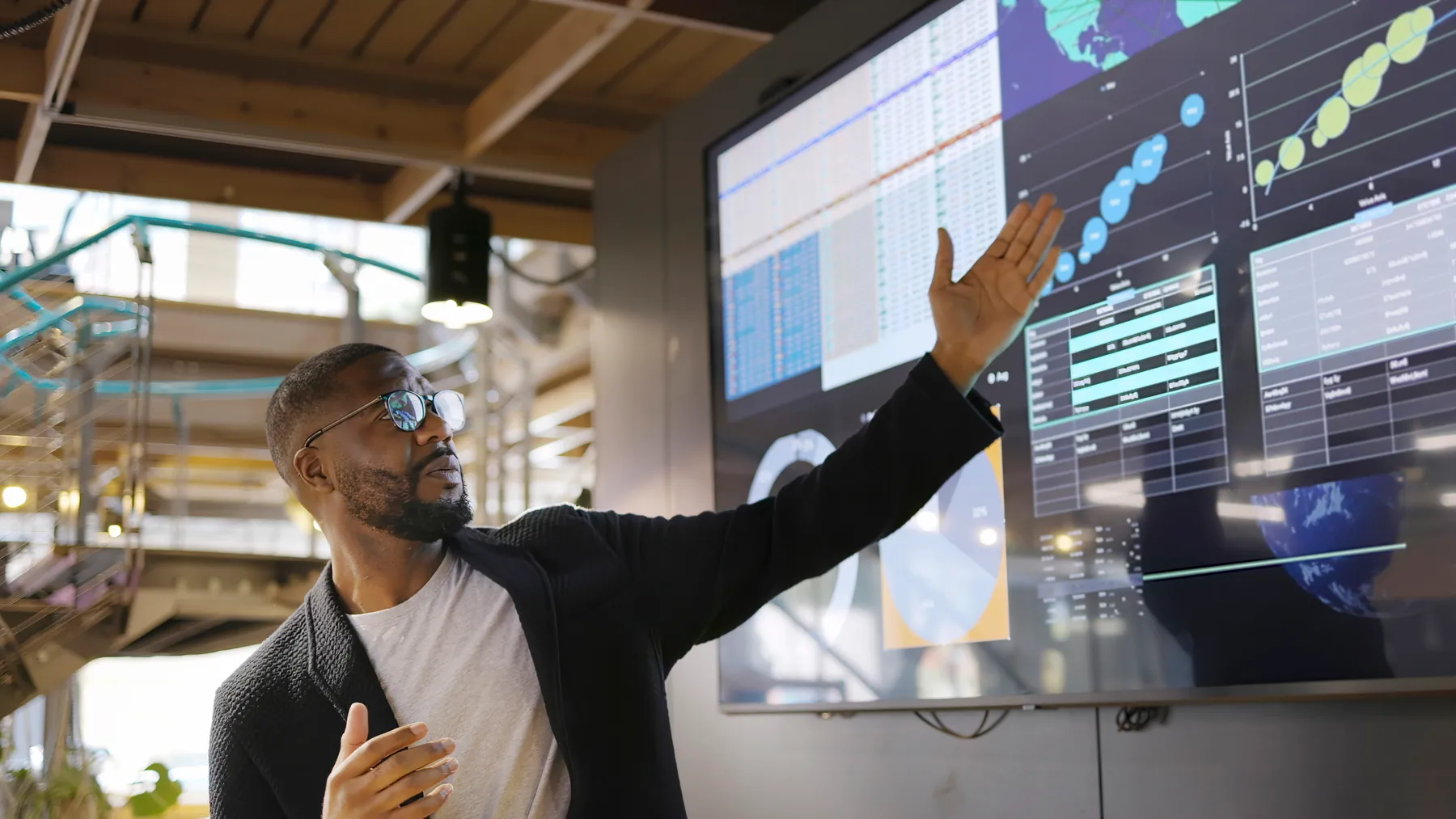 A technology executive presents a data visualization with the aid of a large screen.