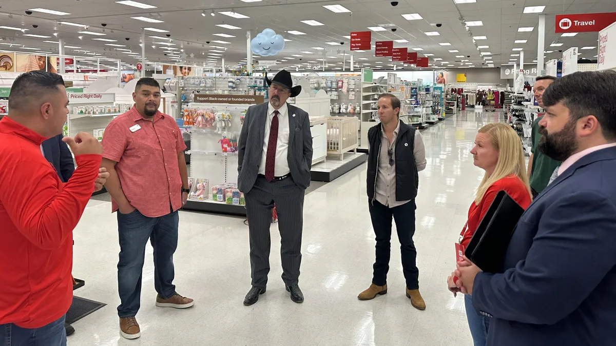 A group of people stand in a store, talking.