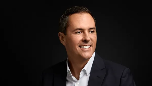 A headshot shows Taylor Patton in dark suit jacket and white shirt against a black background.