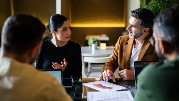 Confident Iranian businesswoman explaining to male colleagues in meeting