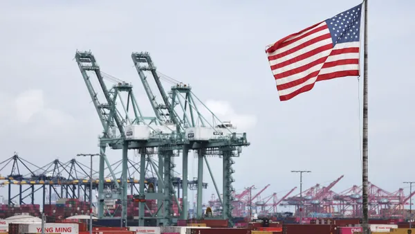 A U.S. flag flies in front of shipping containers and cranes at the Port of Los Angeles on Sept. 26, 2025.