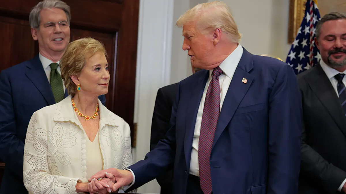 Education Secretary Linda McMahon and President Donald Trump clasp hands as they speak to each other