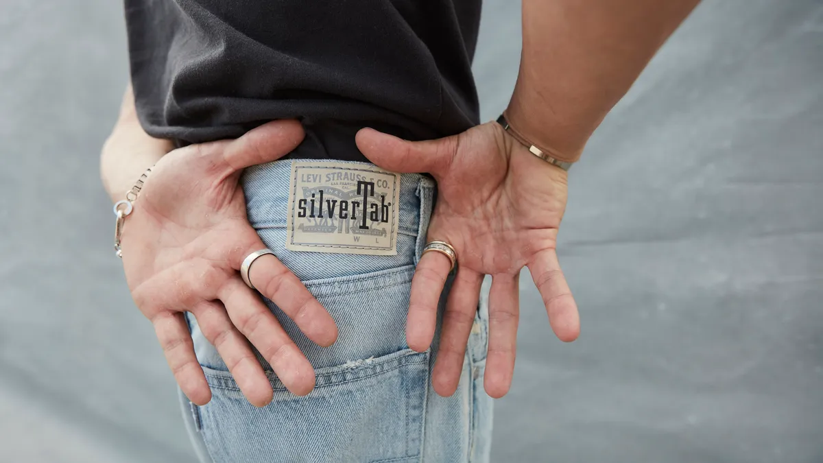 A person wearing jeans frames Levi's SilverTab with their hands.