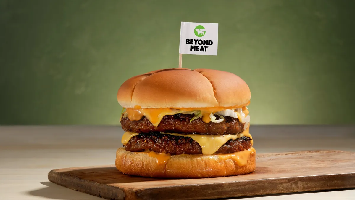 A Beyond Meat double cheeseburger with a toothpick flag of the company's logo sits on a counter.