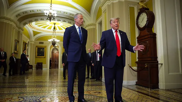 Senate Majority Leader John Thune watches President Donald Trump speak to the media in the U.S. Capitol building.