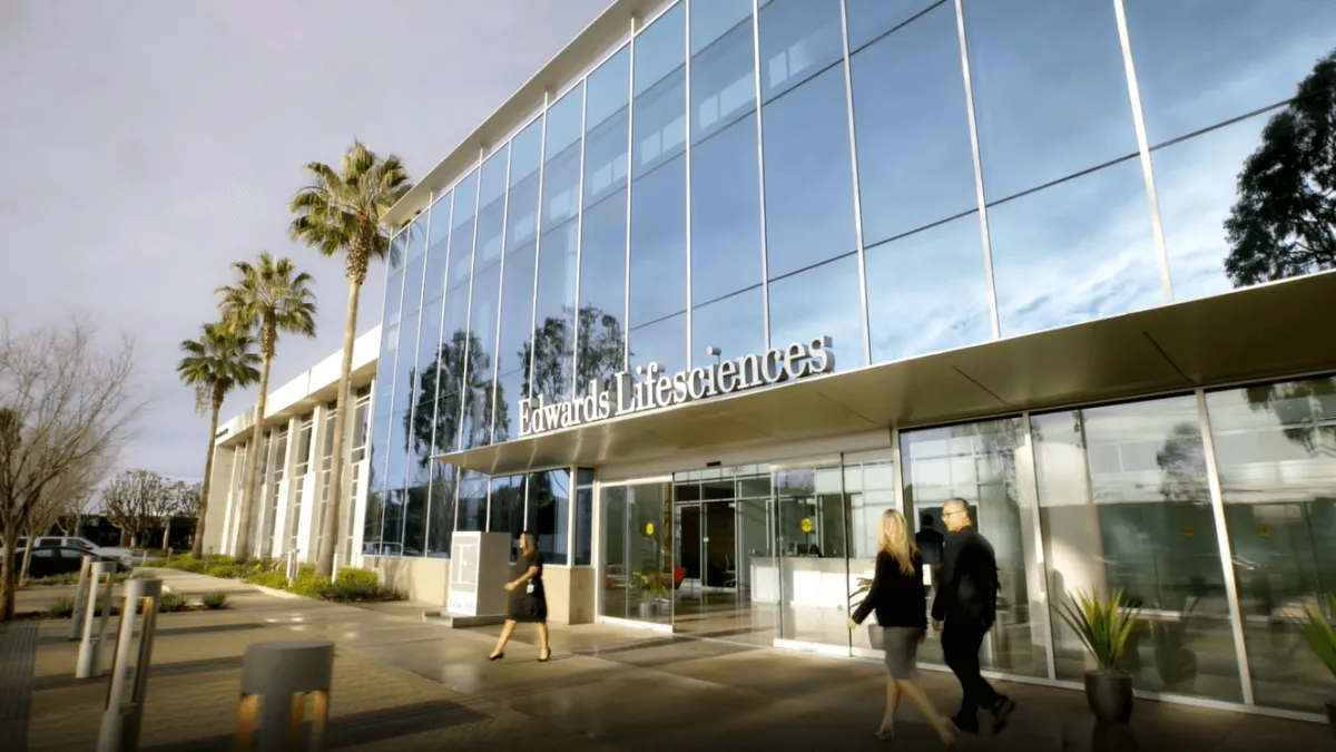 A view of the Edwards Lifesciences headquarters building with three people walking in front.