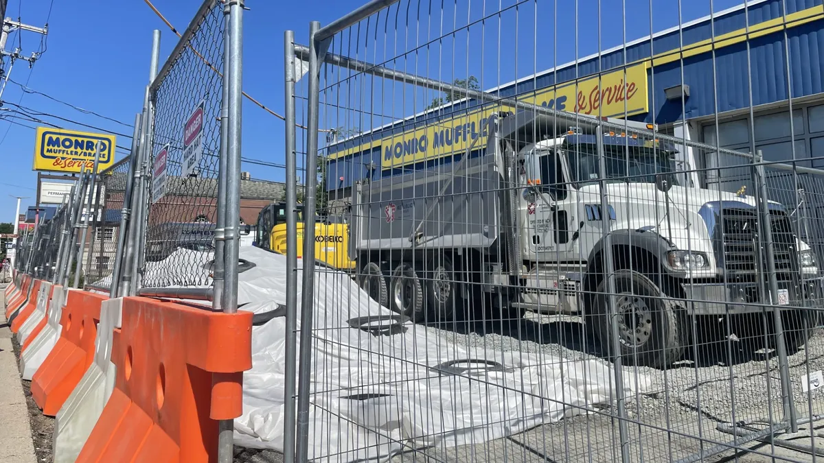 A Republic Services truck sits at a work site behind a chain link fence in Somerville, Mass.