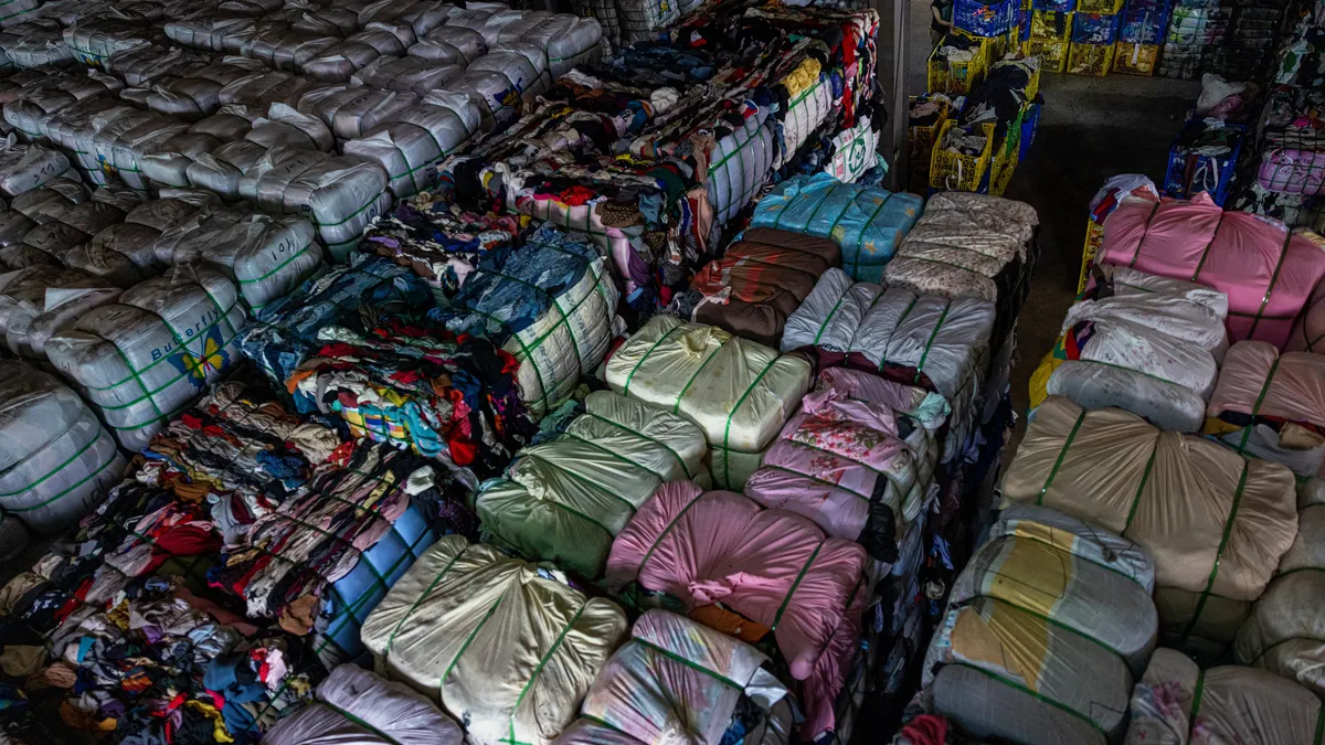 Bales of sorted second-hand clothes piled up at in a warehouse.