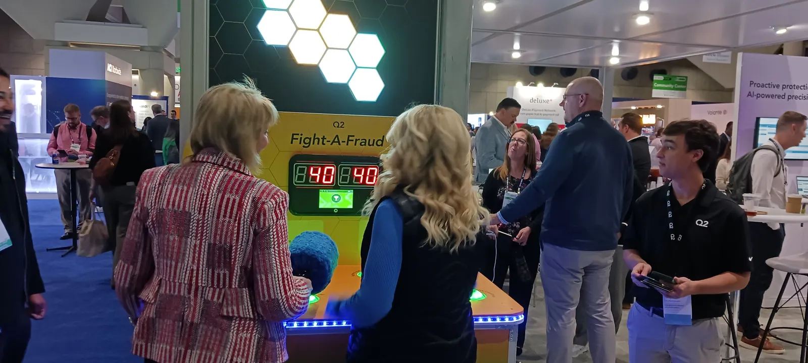 People stand at a game booth with fuzzy hammers.