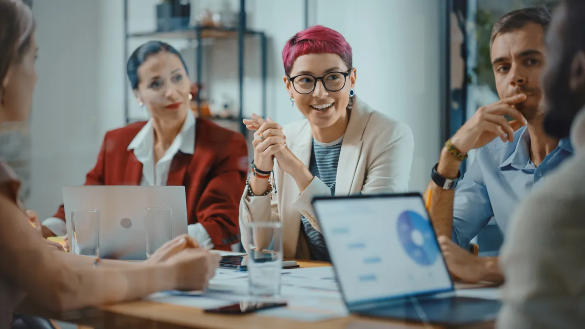 Group of people with laptops having a business meeting at a conference table.