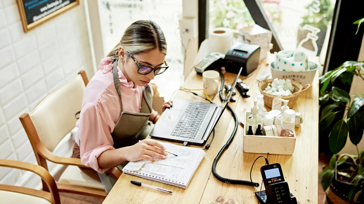 Business owner using laptop in retail shop.