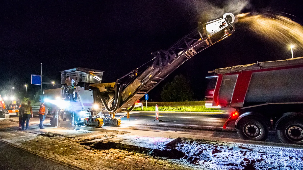 A photo shows activity on a highway construction site at night.