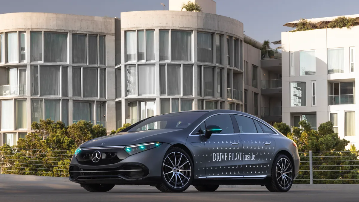 A Mercedes-Benz EQS sedan test vehicle with a Drive Pilot logo on the door.