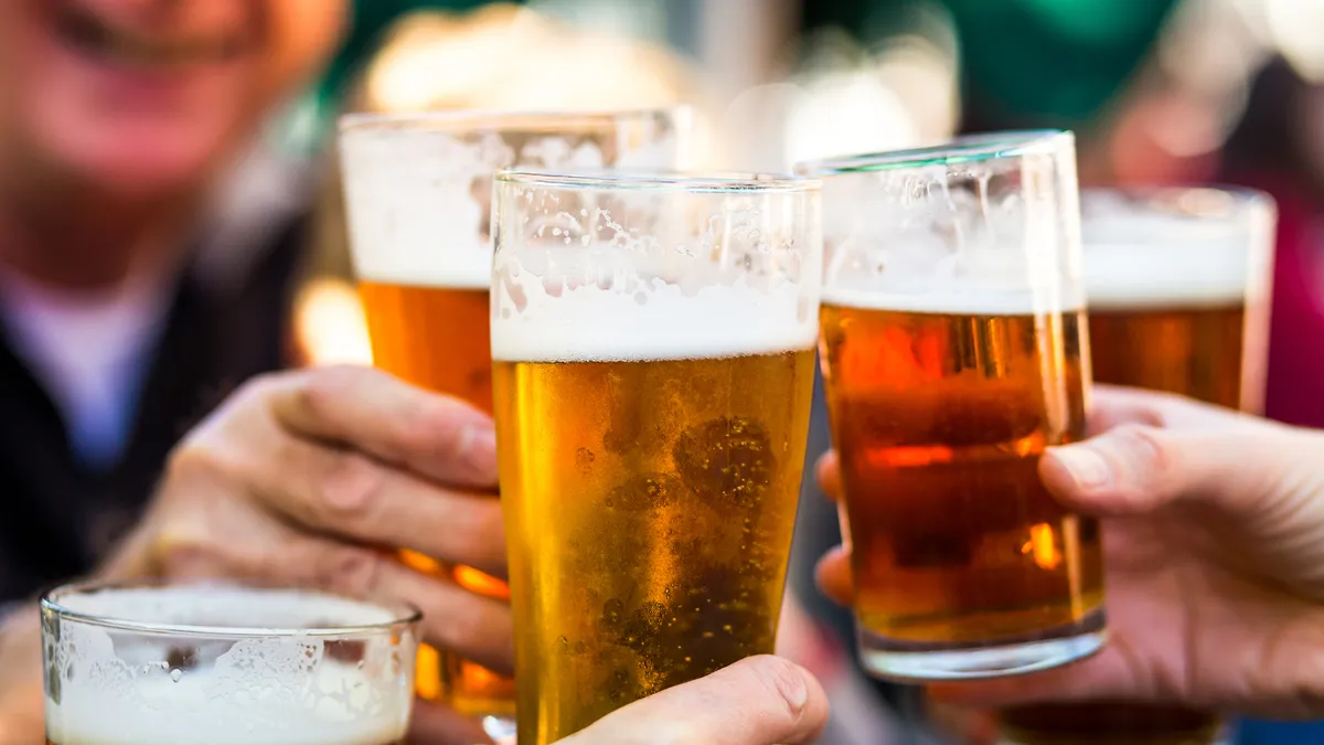 A close up shot of glasses filled with liquid held close together for a toast.