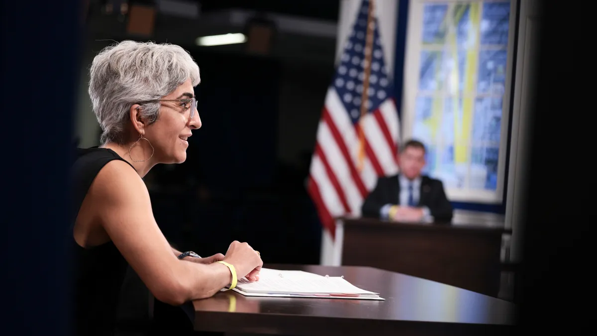 Kiran Ahuja is seen speaking with Marty Walsh in the background.