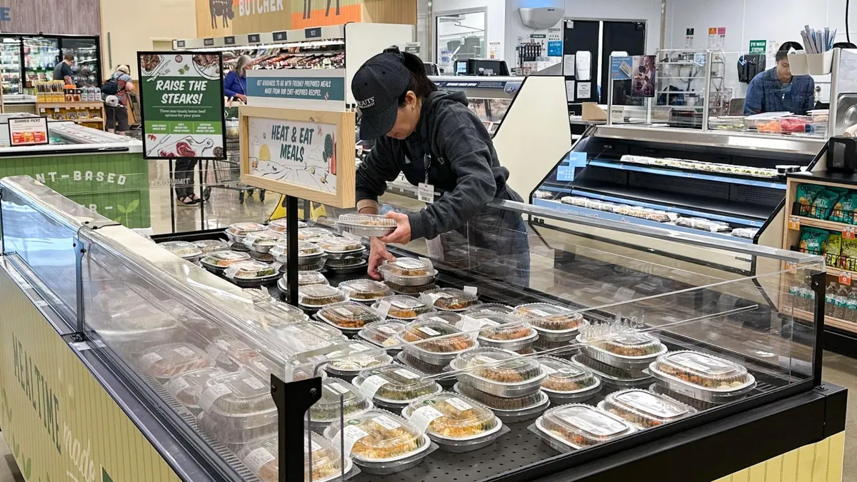 Sprouts employee restocking Heat & Meat meal offerings