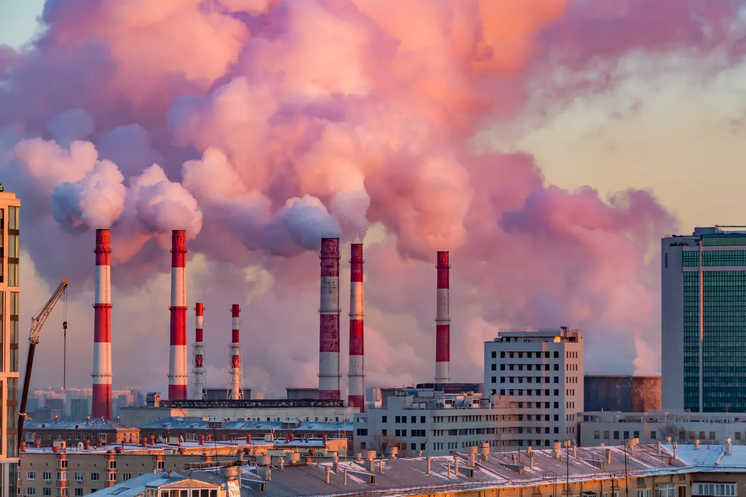 Steam or smoke comes from the pipes. Combined heat and power plant in the city. Landscape at sunset or dawn.