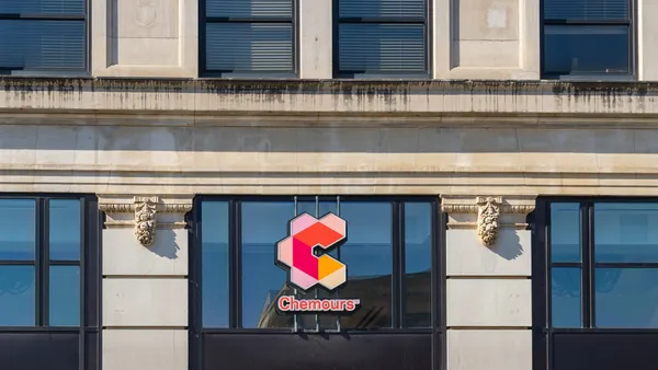 A beige building with dark windows, and the red and orange Chemours logo sign in the center.