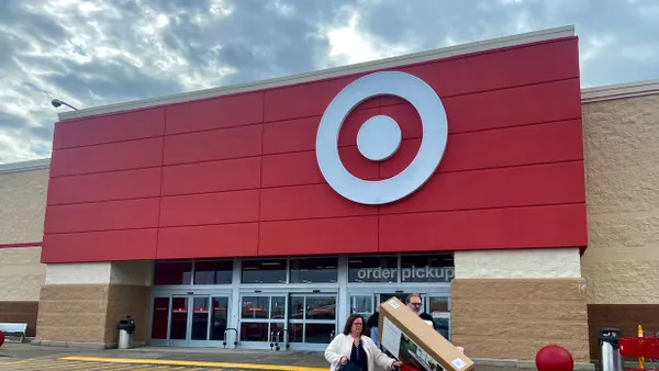 Two people walking out from a store with a cart full of items.