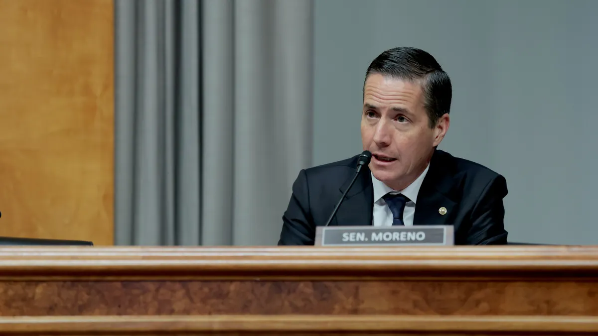 A person in a suit and tie speaks into a microphone.