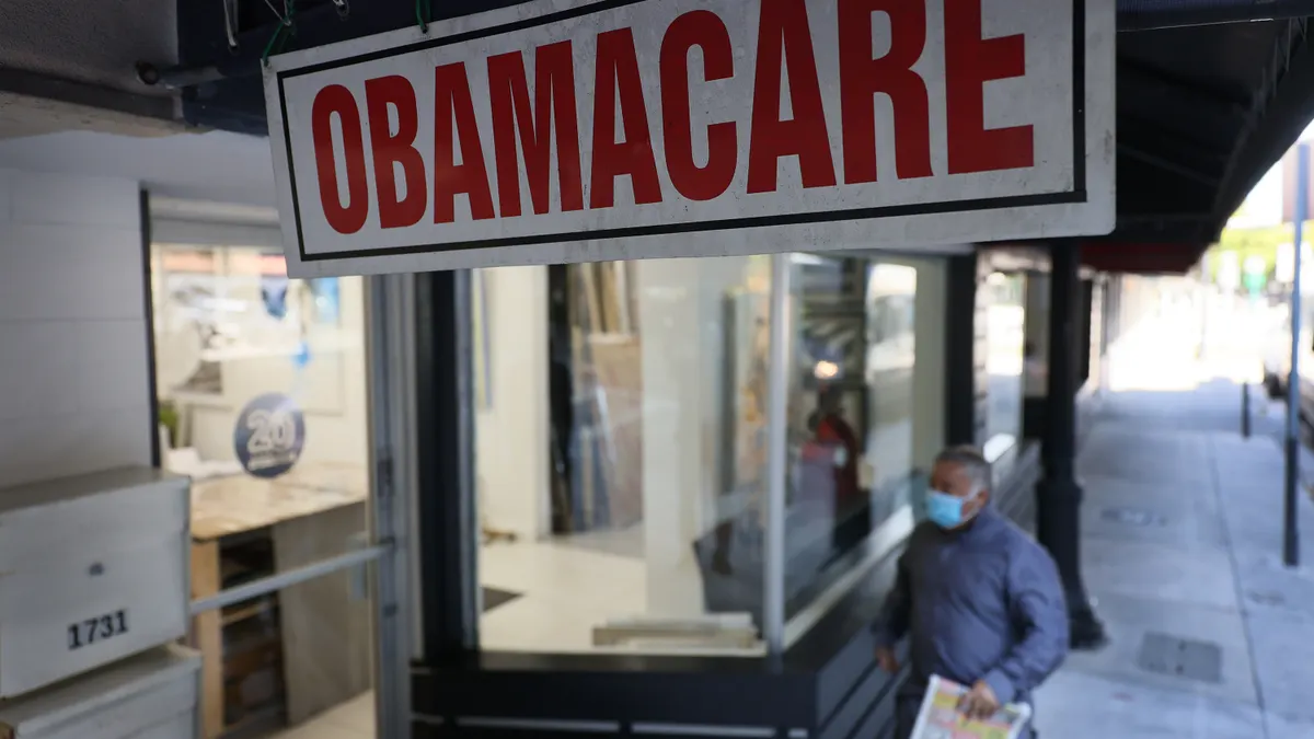A sign reading OBAMACARE hangs outside a storefront.