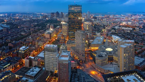 A skyshot of Boston across a dusky view with a river through the left side of the photo.