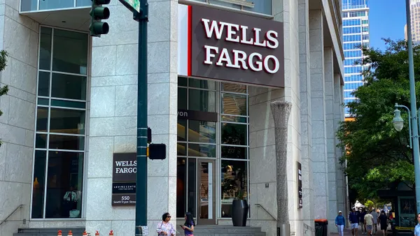 A modern building facade with "Wells Fargo" signage above the entrance is shown, as people pass by on the street.