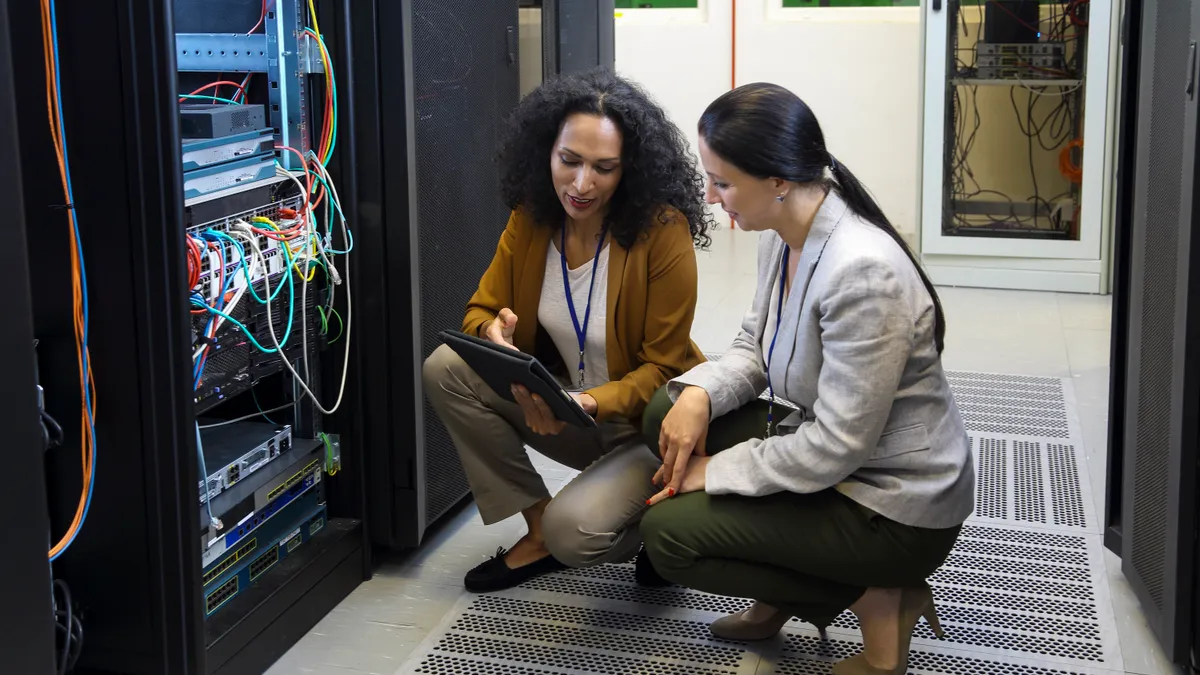 Adult women in data center checking cables and whole network, server setup and programing mainframe through digital tablet.