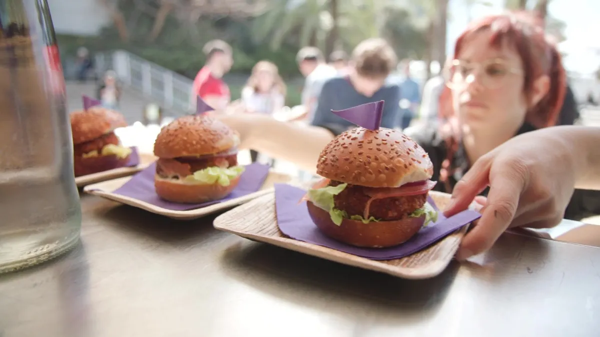 A woman takes two cultivated chicken sandwiches made from SuperMeat's chicken.