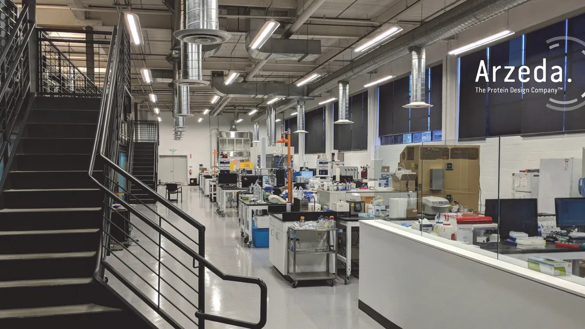 A view of Arzeda's lab, with stairs on the left and several lab tables with equipment on the right.