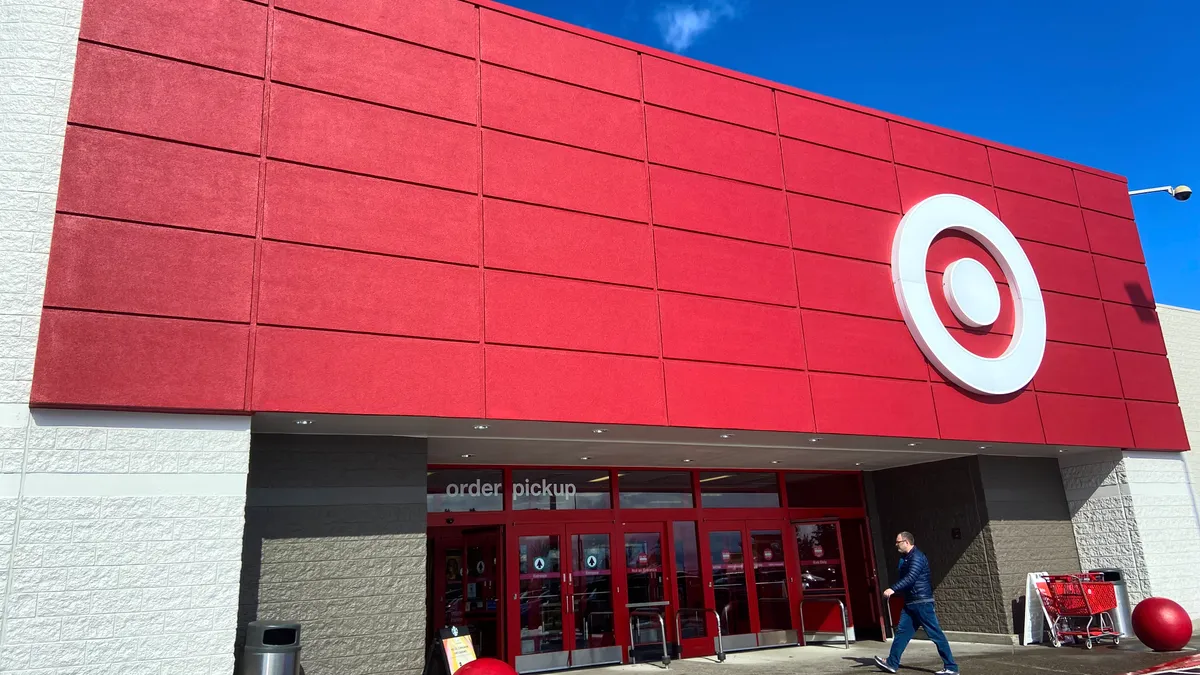 A person walks into a store with a bright red front and a white target sign, its doors trimmed in red.