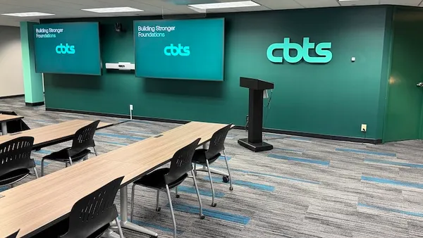The interior of an office with filled with tables and digital screens bearing the CBTS corporate logo.