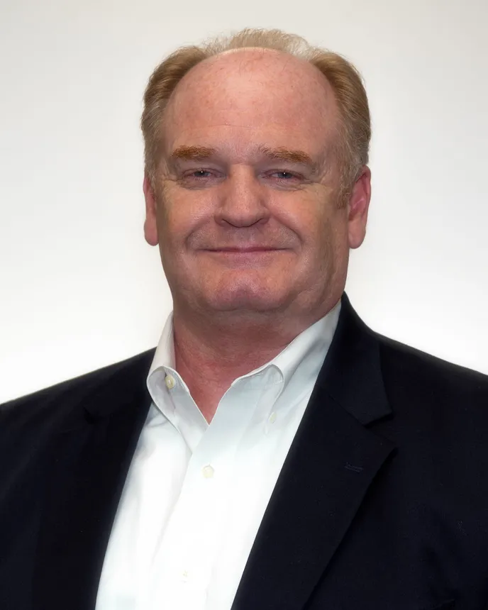 Charlie Prickett, CEO of AAA Cooper Transportation, smiles in a white dress shirt and blue blazer.