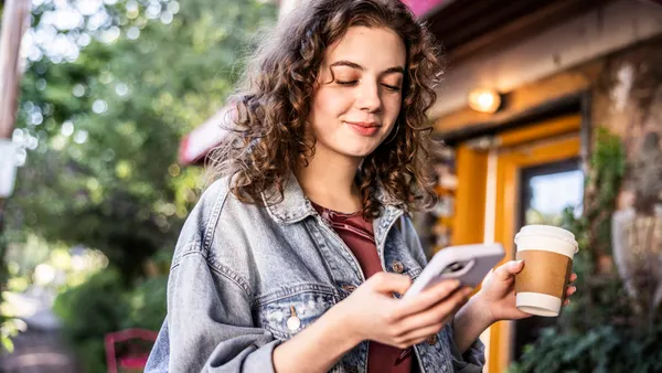 Young woman using smartphone in front of cafe